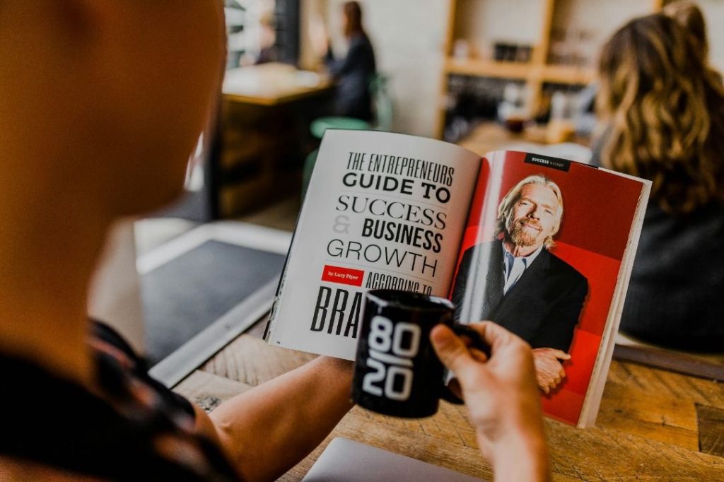 An entrepreneur reading a business growth guide while holding a coffee cup at a cafe